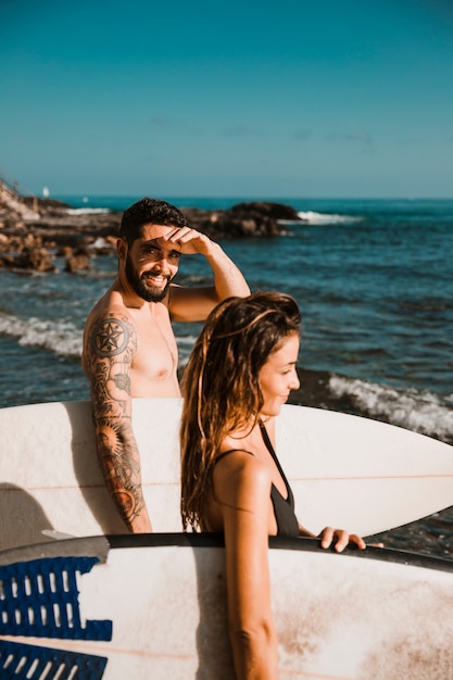 Glimlachende man met surfplank in de buurt van vriendin