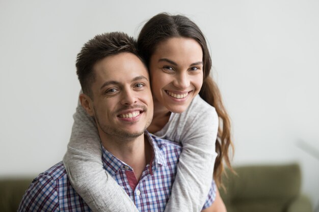 Glimlachende man piggyback vrolijke vrouw die camera bekijkt