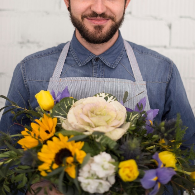 Gratis foto glimlachende mannelijke bloemist met mooi bloemboeket