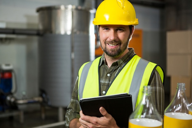 Glimlachende mannelijke werknemer die digitale tablet in fabriek houdt