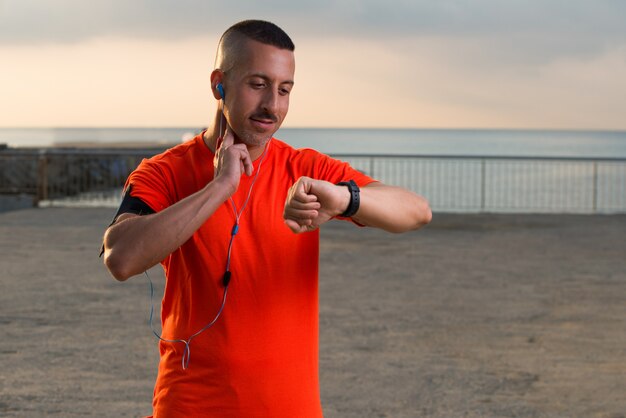 Glimlachende medio volwassen mannelijke atleet kijken naar horloge