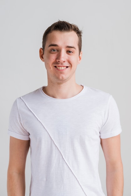 Glimlachende mens die in witte t-shirt camera bekijkt