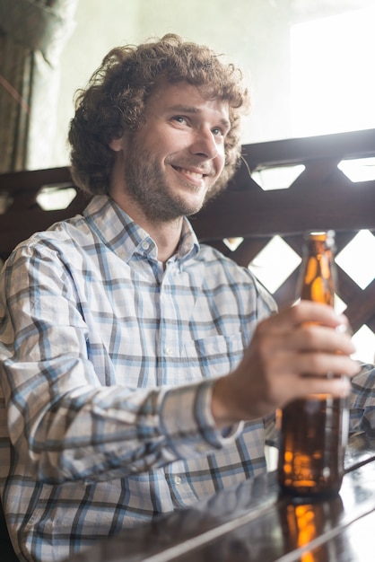 Gratis foto glimlachende mens die met bier weg kijkt