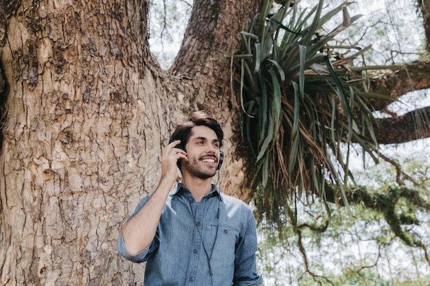 Gratis foto glimlachende mens die op telefoon op aard spreekt