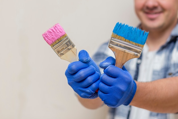 Glimlachende mens die roze en blauwe verfborstel houdt