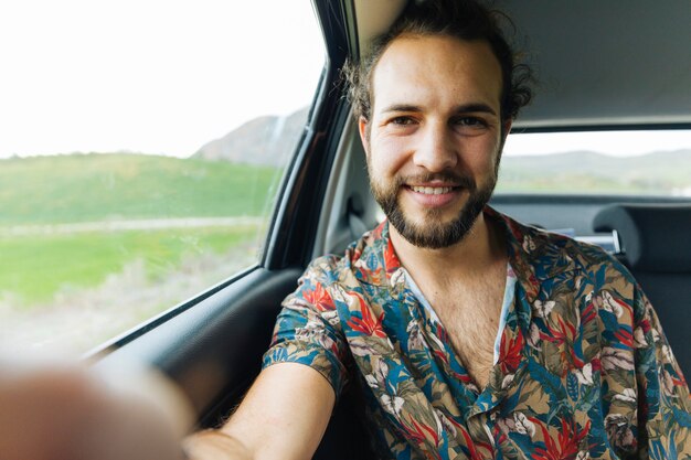 Glimlachende mens die selfie in auto nemen
