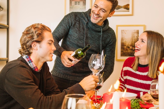 Glimlachende mens met wijnfles bij Kerstmisdiner