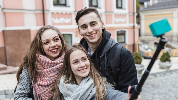 Glimlachende mensen die selfie met stok nemen