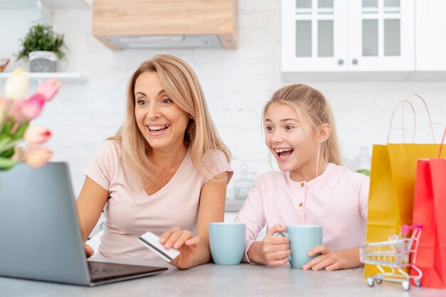 Glimlachende moeder en dochter die op laptop kijken