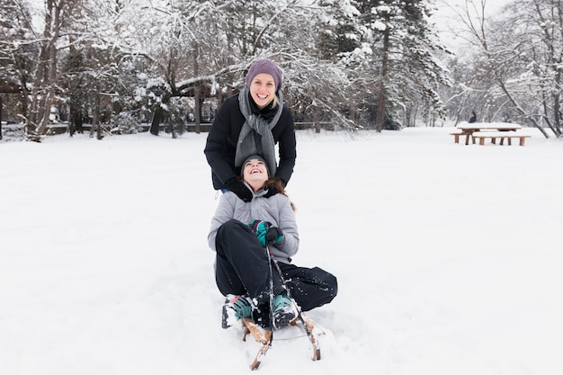 Glimlachende moeder met haar dochter die pret heeft bij de winterdag