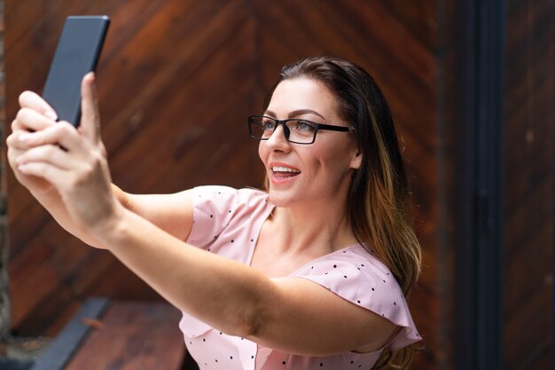 Glimlachende mooie vrouw die selfie foto op smartphone in koffie nemen