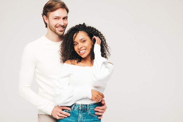 Glimlachende mooie vrouw en haar knappe vriendje. gelukkige vrolijke multiraciale familie met tedere momenten op grijs