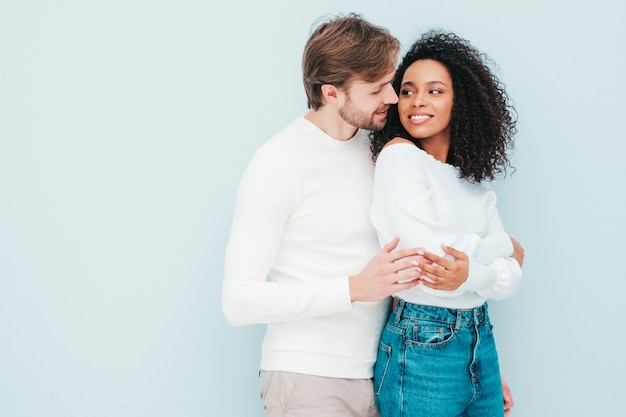 Glimlachende mooie vrouw en haar knappe vriendje. Gelukkige vrolijke multiraciale familie met tedere momenten op grijs