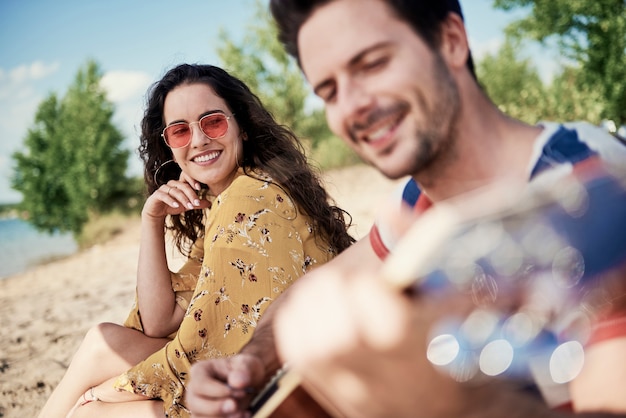 Gratis foto glimlachende mooie vrouw zittend op deken op het strand