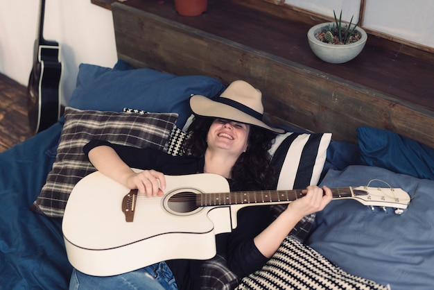 Gratis foto glimlachende musicus met gitaar op bed