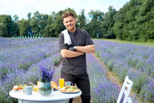 Glimlachende ober poseren in lavendelveld in de buurt van tafel