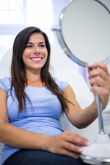 Glimlachende patiënt die in de spiegel kliniek bekijken