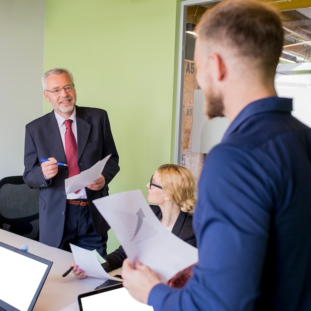 Glimlachende rijpe zakenman die bespreking met grafiek hebben