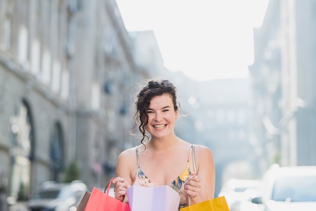 Glimlachende shopaholic vrouw met kleurrijke papieren zakken