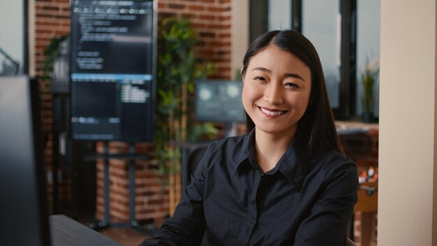 Glimlachende softwareontwikkelaar die machine learning-app-code typt op het toetsenbord van de computer, zittend aan een bureau in big data office. Vriendelijke cloudprogrammeur die nonchalant werkt in een cyberbeveiligingsbureau.