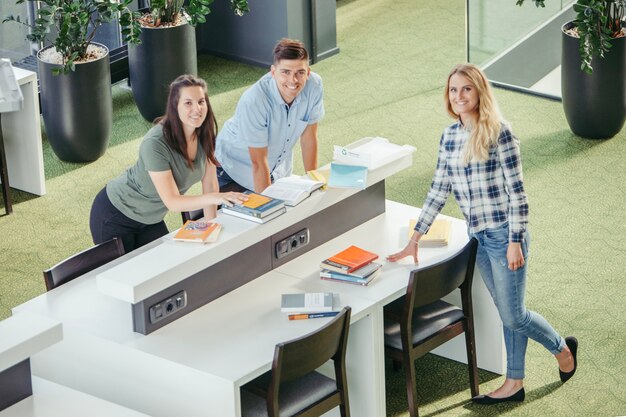 Glimlachende studenten kijken naar camera in de bibliotheek