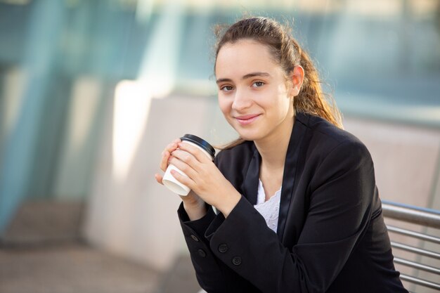 Glimlachende succesvolle vrouwelijke manager die van koffiepauze geniet