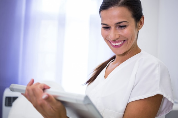 Glimlachende tandarts die digitale tablet gebruiken