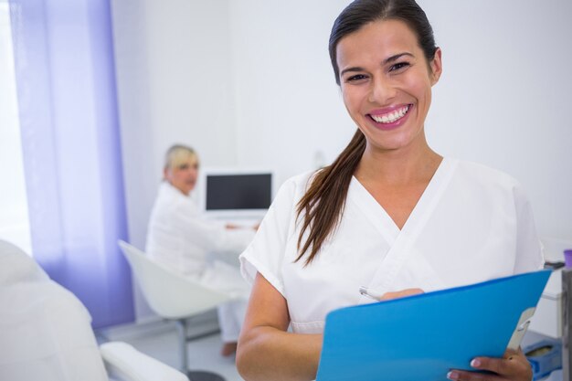 Glimlachende tandarts die een medisch rapport schrijft