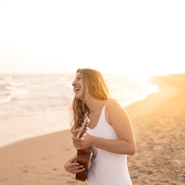 Glimlachende tiener het spelen ukelele bij strand