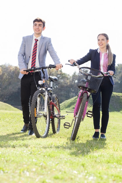 Glimlachende tieners die hun fietsen op een zonnige dag