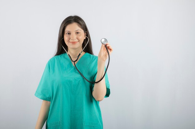 Glimlachende verpleegster die stethoscoop draagt en met hand houdt.