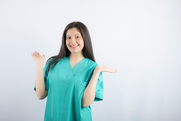 Glimlachende verpleegstervrouw die haar hand omhoog houdt en kijkt