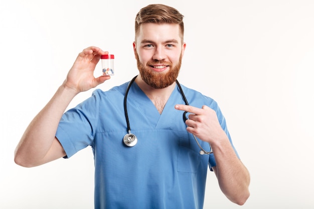 Glimlachende vriendschappelijke apotheker die vinger richten op fles met tabletten