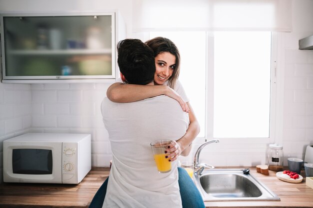 Glimlachende vrouw die de mens in keuken koestert