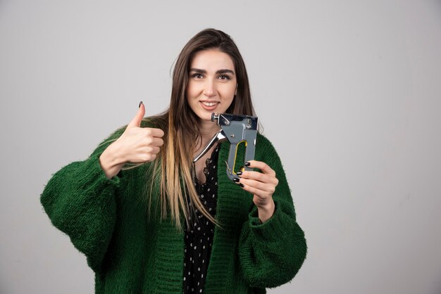 Glimlachende vrouw die een duim toont en een werkend hulpmiddel houdt.