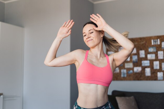 Glimlachende vrouw die in het midden van de woonkamer dansen die van zich en van het leven genieten