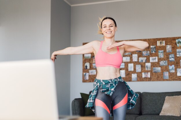 Glimlachende vrouw die in het midden van de woonkamer dansen die van zich en van het leven genieten