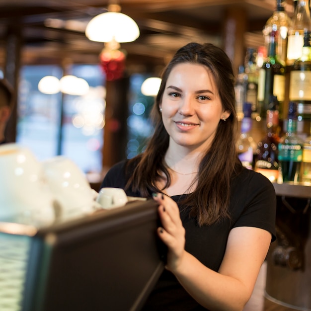 Glimlachende vrouw die koffiemachine met behulp van