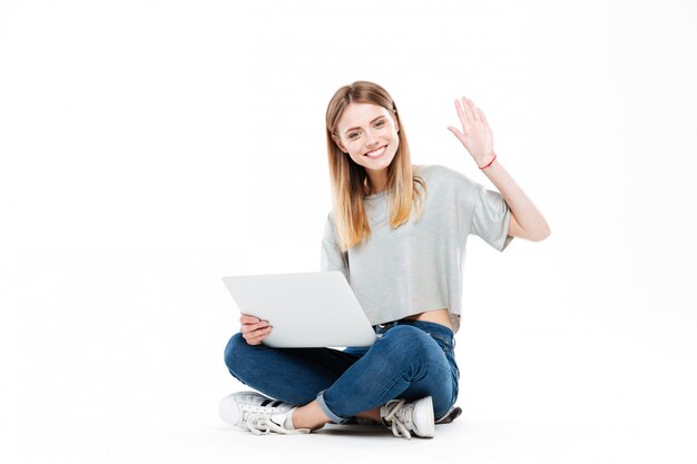 Glimlachende vrouw die laptop computer met behulp van