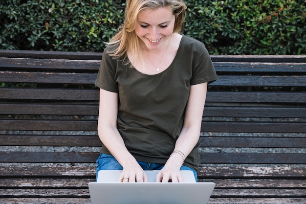 Glimlachende vrouw die laptop op bank met behulp van