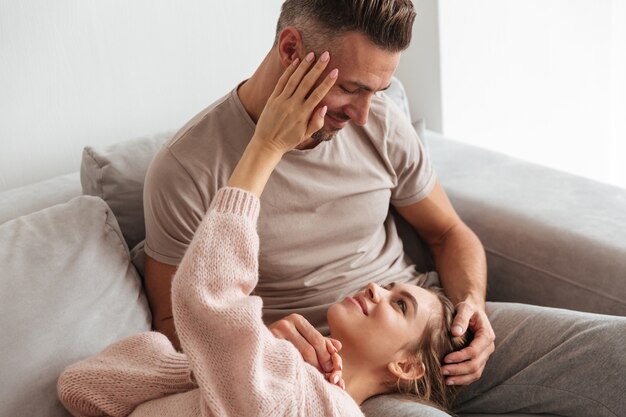 Glimlachende vrouw die op benen van haar vriend thuis op laag ligt