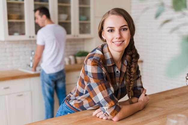 Glimlachende vrouw die op lijst leunt terwijl man afwas