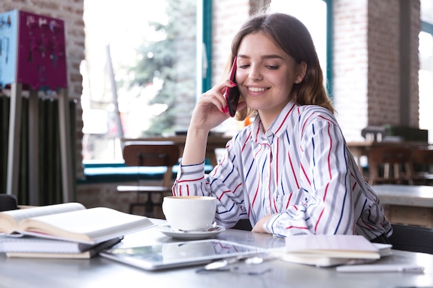 Glimlachende vrouw die op smartphone spreekt