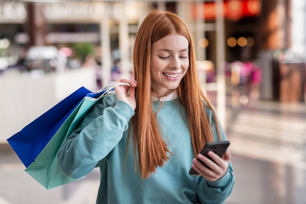 Glimlachende vrouw die op telefoon kijkt