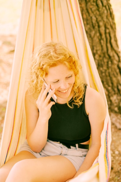 Glimlachende vrouw die op telefoon spreekt