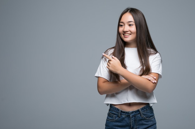 Glimlachende vrouw die vingerkant geïsoleerd portret op grijze achtergrond richten.