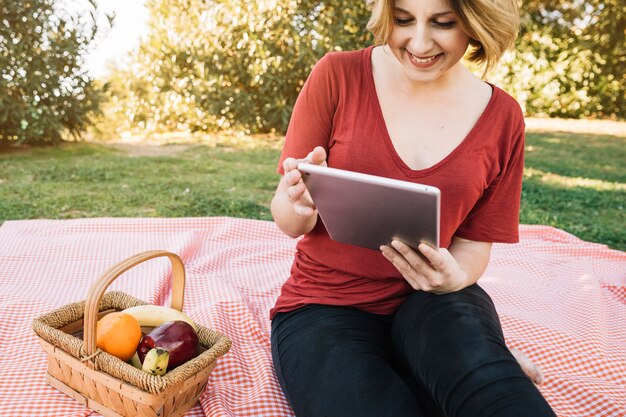 Glimlachende vrouw het doorbladeren tablet op picknick