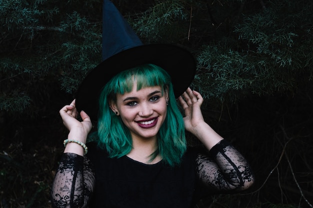 Glimlachende vrouw in heks hoed in het bos