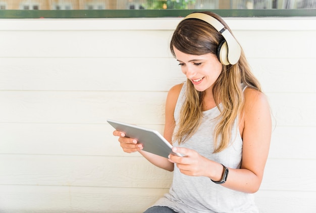 Glimlachende vrouw in hoofdtelefoons die tablet gebruiken