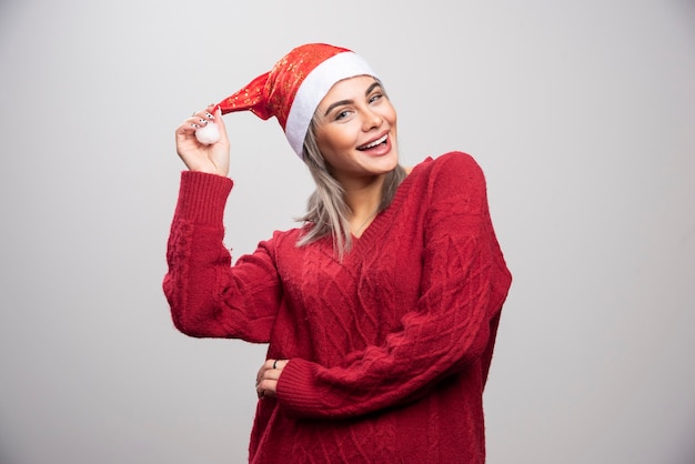 Glimlachende vrouw in kerstmuts die zich voordeed op een grijze achtergrond.
